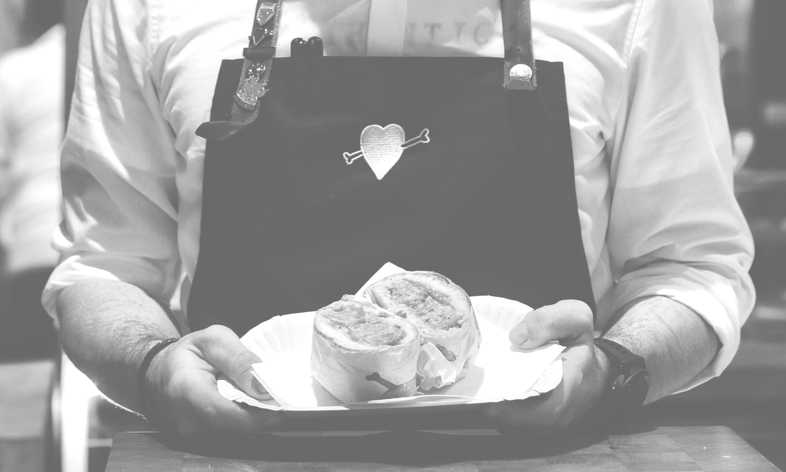 Chef holds a plate with a sandwich on it.