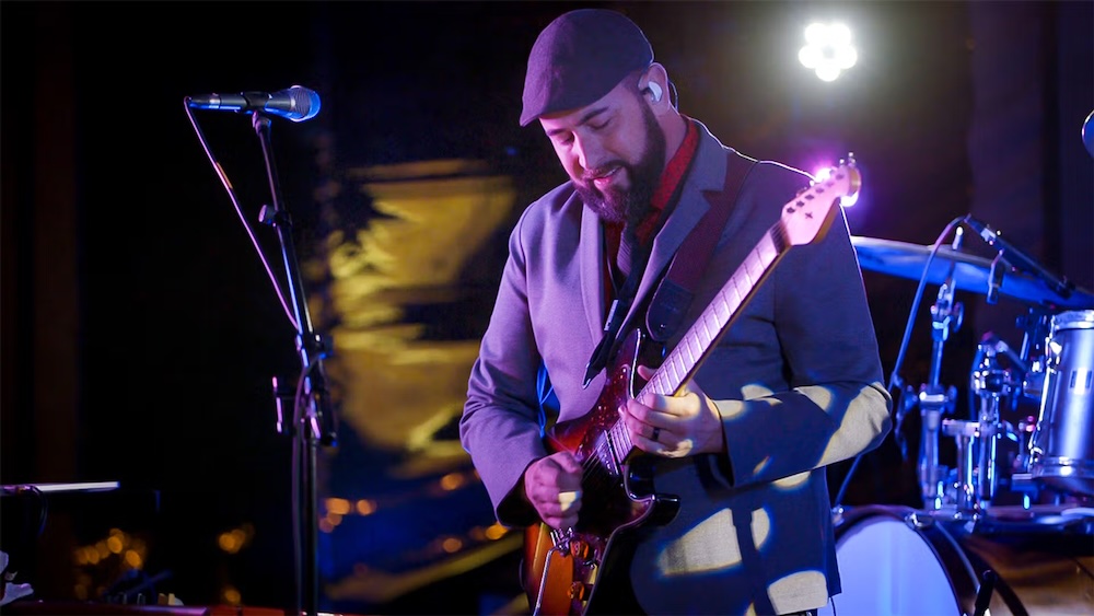 Rich Gunderlock plays electric guitar on stage