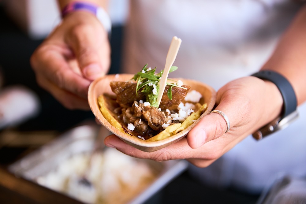 A chef holds a taco out to a guest at Team Hidi