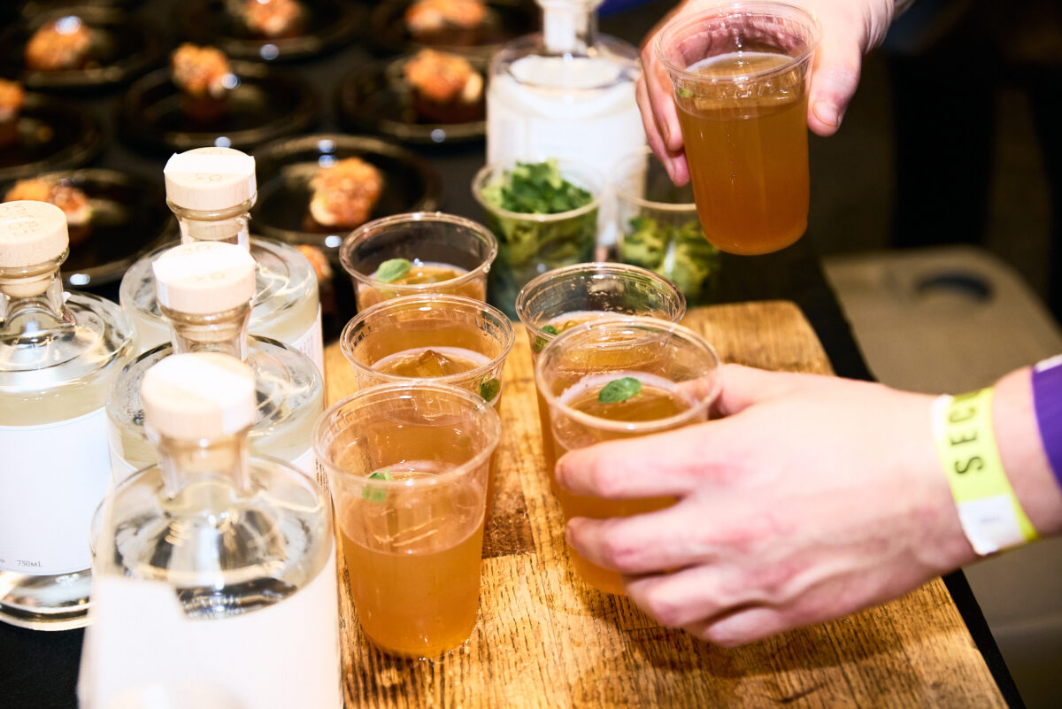 Guests pick up cocktails from a table at Team Hidi