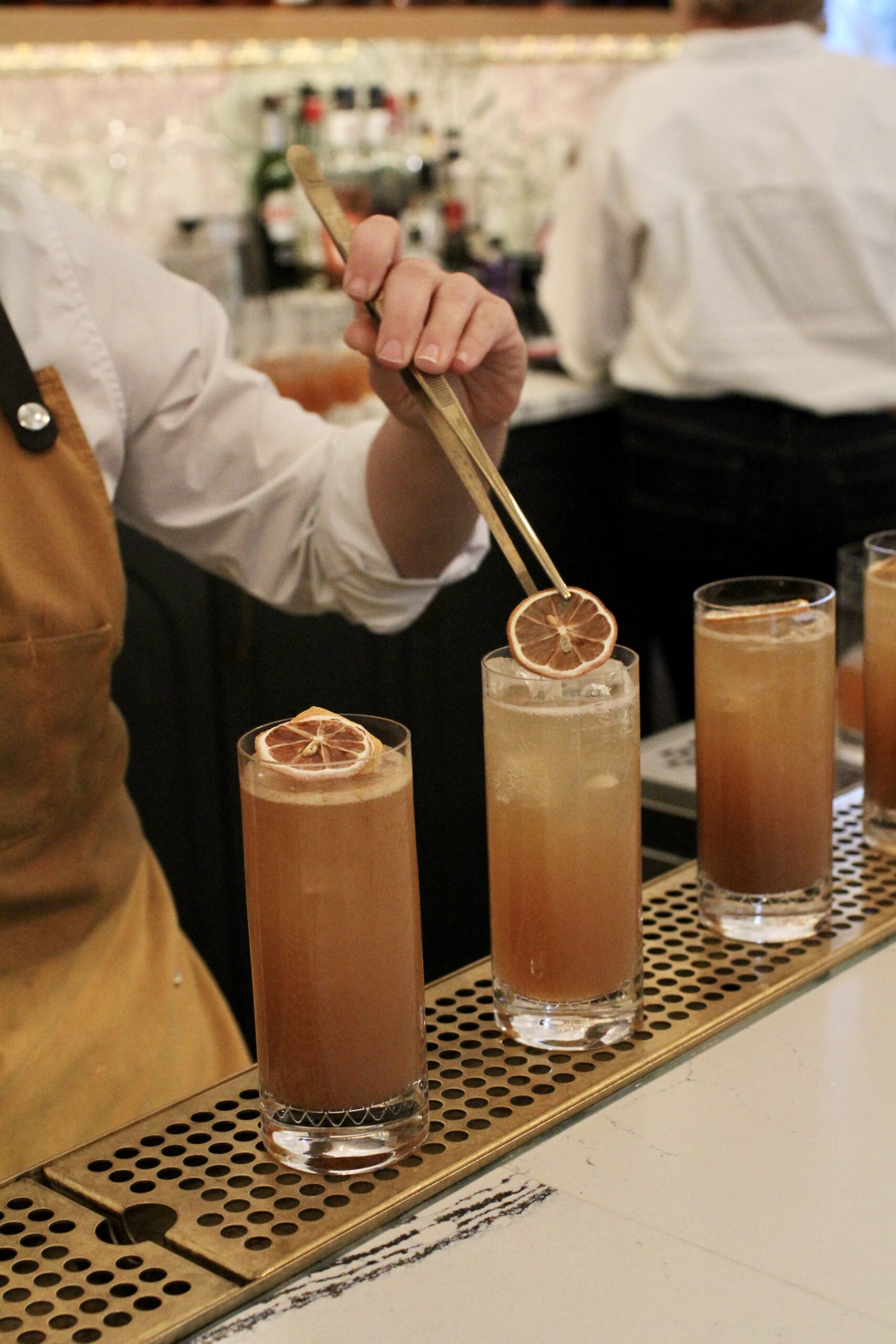 Bartender uses tweezers to place a garnish on a cocktail at Charlotte Family Meal